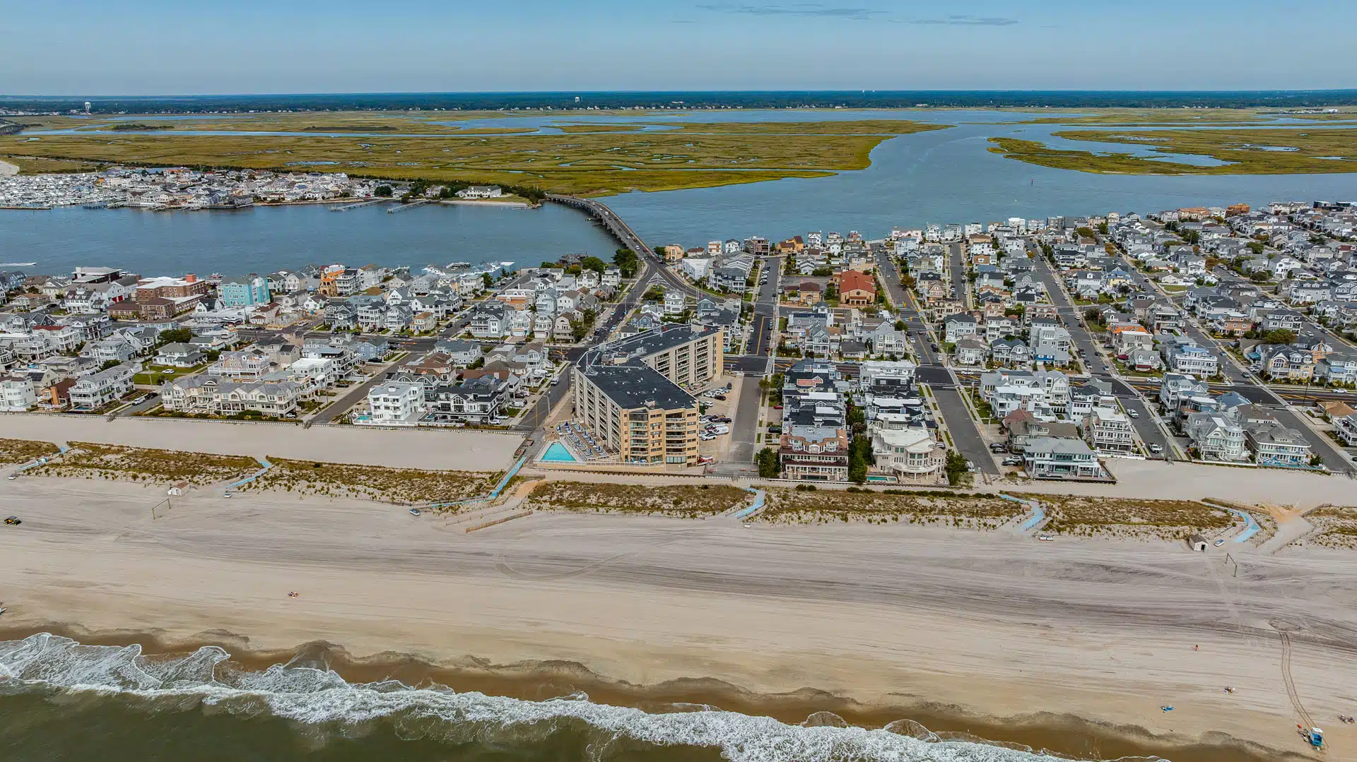 Aerial view of the Longport, NJ beach with homes, the bay and the bridge behind